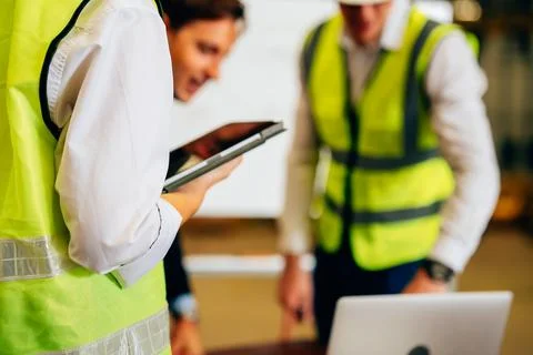 Warehouse engineer with safety vest using tablet for checking goods on shelves Stock Photos