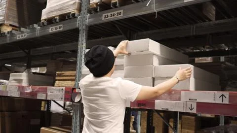 Warehouse large storage or cargo for distribution and man is picking up a box Stock Photos