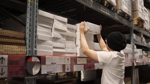 Warehouse large storage or cargo for distribution and man is picking up a box Stock Photos