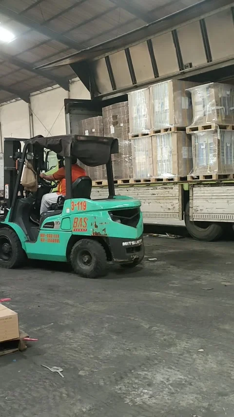 Warehouse Logistics: Forklift Unloading Goods from Truck Stock Footage 303370151