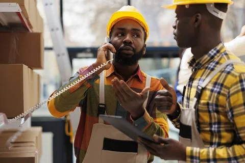 Warehouse logistics operator managing parcel dispatching on telephone Stockfoto's