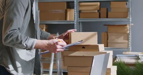 Warehouse male worker receiving, fixing, incoming boxes, picking orders from Stock Footage 272904865