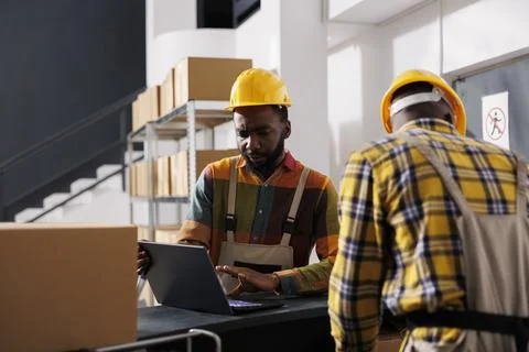 Warehouse manager checking parcel delivery electronic invoice on laptop Stockfoto's