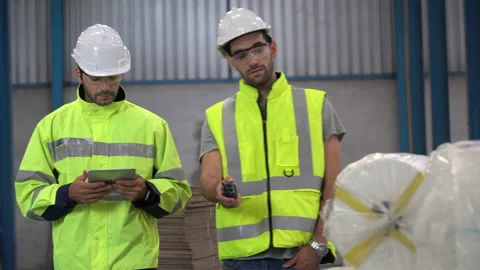 Warehouse manager holding walkie talkie walking with warker man using tablet Stock Footage 144266853