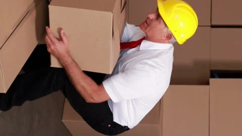 Warehouse manager injuring his back moving boxes Stock Footage 302234976