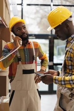 Warehouse manager listening to supervisor explaining inventory on phone Stockfoto's