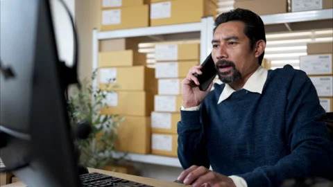 Warehouse manager multitasking with phone call Stock Footage 326277242