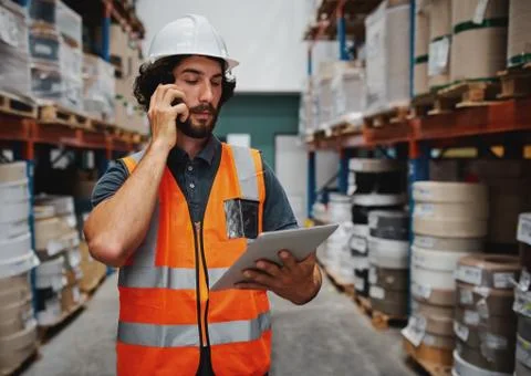 Warehouse manager tracking supply order details using digital tablet while in Stock Photos