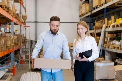 Warehouse Managers Holding Box and Clipboard in Distribution Center Stock Photos
