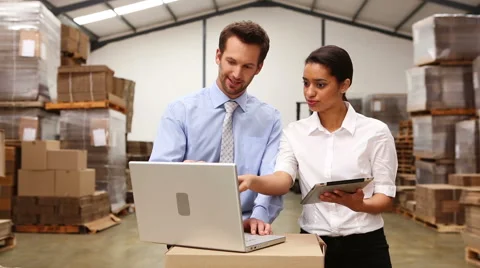 Warehouse managers looking at tablet pc and laptop Stock Footage 43162968