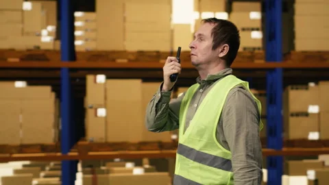 Warehouse operator reporting parcel status via two-way portable transceiver Stock Footage 332911153
