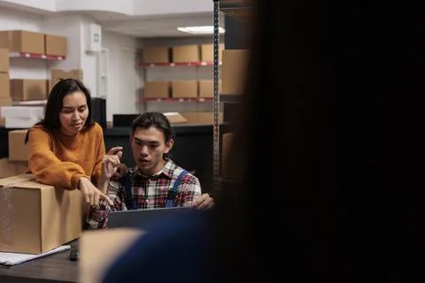 Warehouse package handlers analyzing order pick ticket on laptop 写真素材