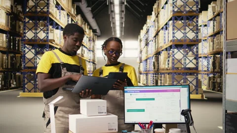 Warehouse staff overseeing parcels tracking info on laptop and tablet 스톡 동영상 315542772