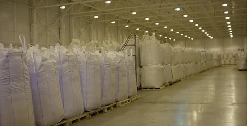 Warehouse for storage of fertilizers in bags. stack of big bag contain rice in Stock Footage 76407977