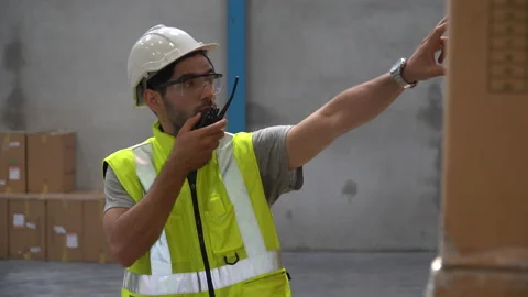Warehouse storage worker  speaking through walkie-talkie checking list and in Stock Footage 146818420