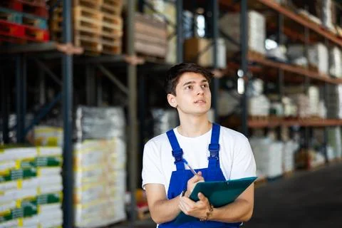 In warehouse of store, guy checks quantity of goods and receipt documents for Stock Photos
