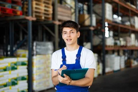 In warehouse of store, guy checks quantity of goods and receipt documents for Stock Photos