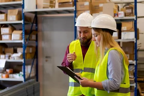 Warehouse supervisor explaining inventory process to female colleague 写真素材