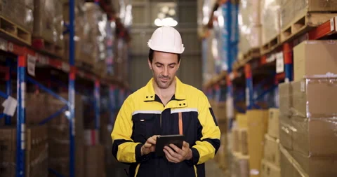 Warehouse supervisor slowly walks between cargo shelves while using digital Vídeo Stock 331126968