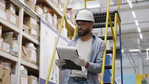 Warehouse supervisor taking inventory on a ladder Video stock 336965440