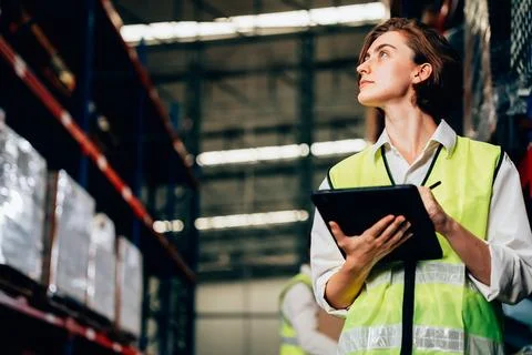 Warehouse supervisor using tablet for controlling and checking goods on shelves 写真素材