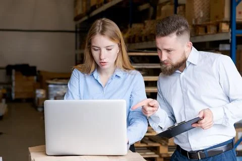 Warehouse Team Analyzing Stock Data on Laptop and Clipboard in Logistics Cent Foto stock