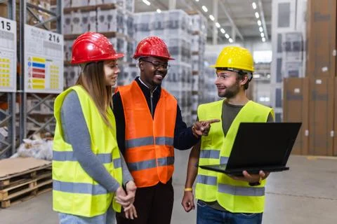Warehouse team discussing logistics while reviewing data on a laptop Foto stock
