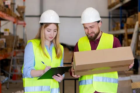 Warehouse team verifying package delivery with inventory checklist 库存照片