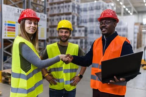 Warehouse teamwork with engineers shaking hands and discussing logistics Stock Photos