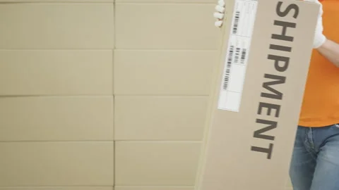Warehouse worker with big parcel with printed SHIPMENT text and label on it Stock Footage 135419454