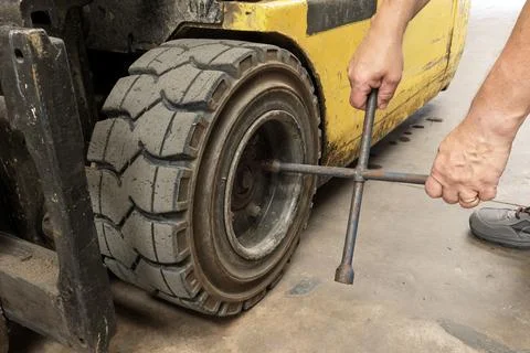 Warehouse Worker Changing Forklift Tyre Using Wrench Stock-Fotos