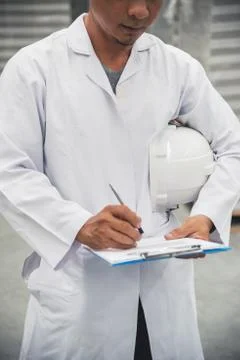 Warehouse worker checking his list on clipboard in a large warehouse factory Foto stock