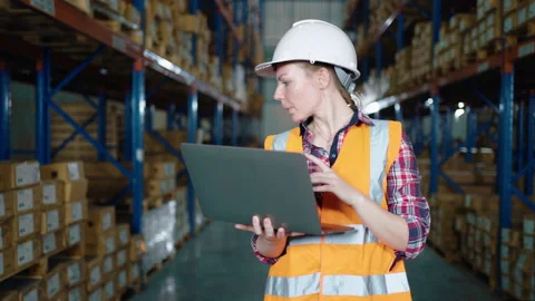 Warehouse worker checking the package using laptop in distribution warehouse Stock Footage 163348429