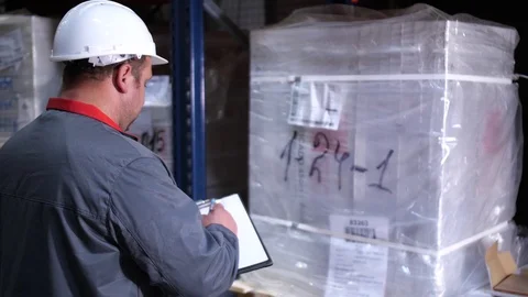 A warehouse worker in a helmet writes his note into his folder. 4K Slow Mo Stock-Footage 111768219