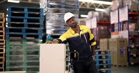 Warehouse worker leans on box and rests during slowmotion scene inside storage Stock Footage 324774336