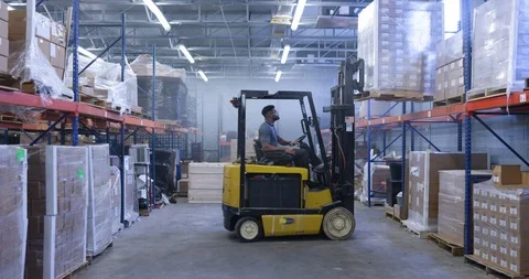 Warehouse worker lifting a shipment pellet with forklift in warehouse Stock Footage 116369121