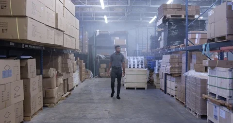 Warehouse worker looking around the merchandise while walking in warehouse Stock Footage 116364522