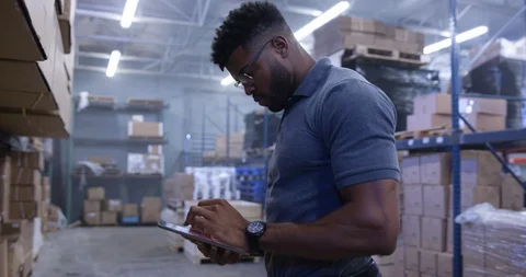 Warehouse worker looking at storage racks noting down the merchandise records Stock Footage 116363832