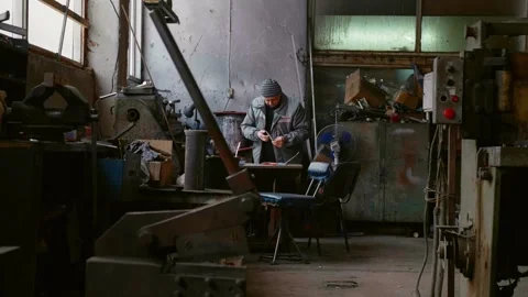 Warehouse worker looking through stuff surrounded by metal machines. Video stock 296542258