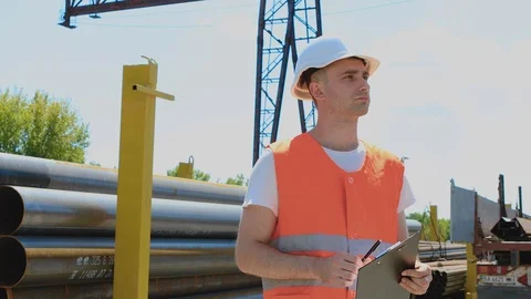 A warehouse worker makes notes on paper. Worker in uniform at metal depot, man Stock Footage 124482249