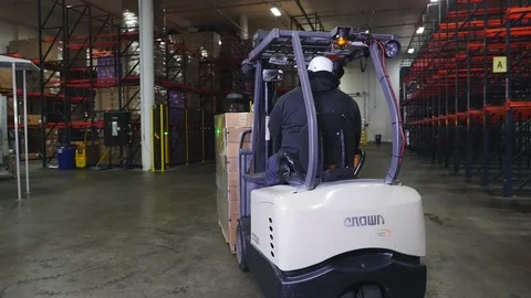 Warehouse worker. Moving palette of boxes with forklift for storage Stock Footage 101976320