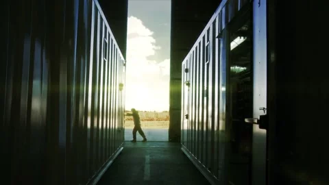 Warehouse Worker Opening Metal Gate in an Industrial Facility, Backlit Interior Stock Footage 100232703