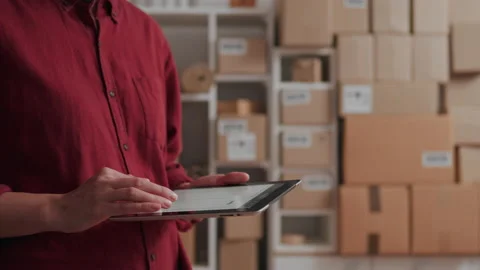 Warehouse worker in overalls holding an electronic tablet entering data of d Stock Footage 224727831