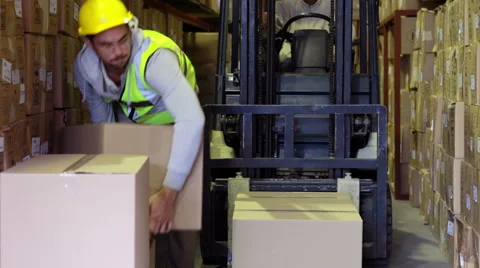 Warehouse worker packing boxes on forklift Stock Footage