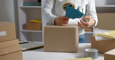 Warehouse worker packs a box of goods for courier delivery.  Stock Footage 166523356