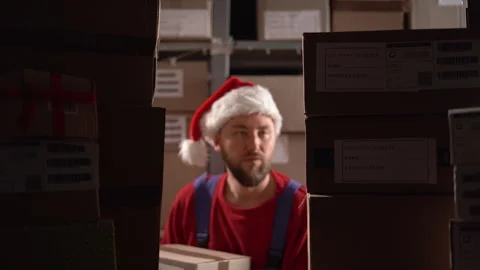 Warehouse worker puts cardboard box shelves full of cardboard boxes and parcels 스톡 동영상 248276143
