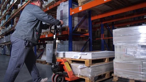 Warehouse worker puts pallets. A man works with a manual forklift. 4K Slow Mo Vídeo Stock 111767563