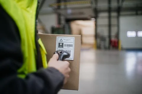 Warehouse worker scanning barcode on cardboard box. Receiving clerk holding Stock Photos