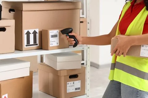 Warehouse worker scanning barcode on a cardboard box for inventory management Stock Photos