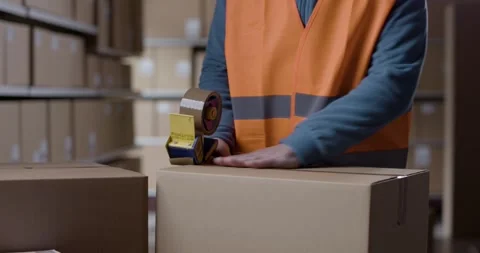 Warehouse worker sealing a box with tape Stock Footage 297855959